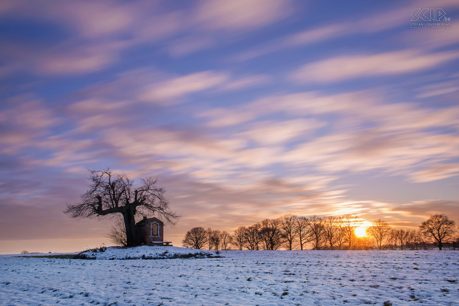 Winter in Sint-Pieters-Rode - Sunset at the chapel The small chapel of Saint Joseph is located in a field under an old linden tree nearby the castle of Horst (Sint-Pieters-Rode, Belgium). It has been built in the beginning of the 19th century. This long exposure shot is made a sunset.<br />
 Stefan Cruysberghs